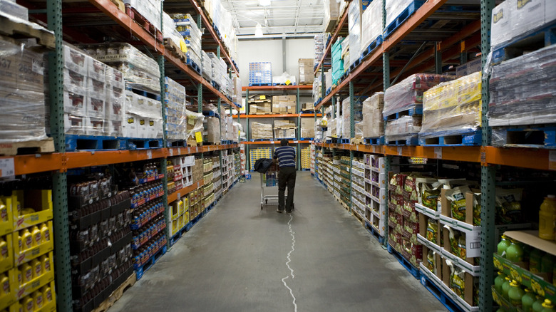 A shopper walking down an aisle inside a Costco store