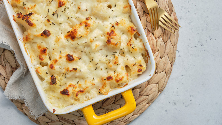 Top view of a mac and cheese casserole with cauliflower in a yellow dish on a counter