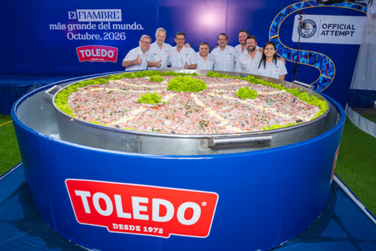 The organizers standing next to the largest fiambre salad